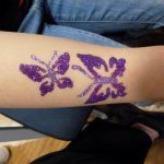 Glitzernder Schmetterling auf der Haut